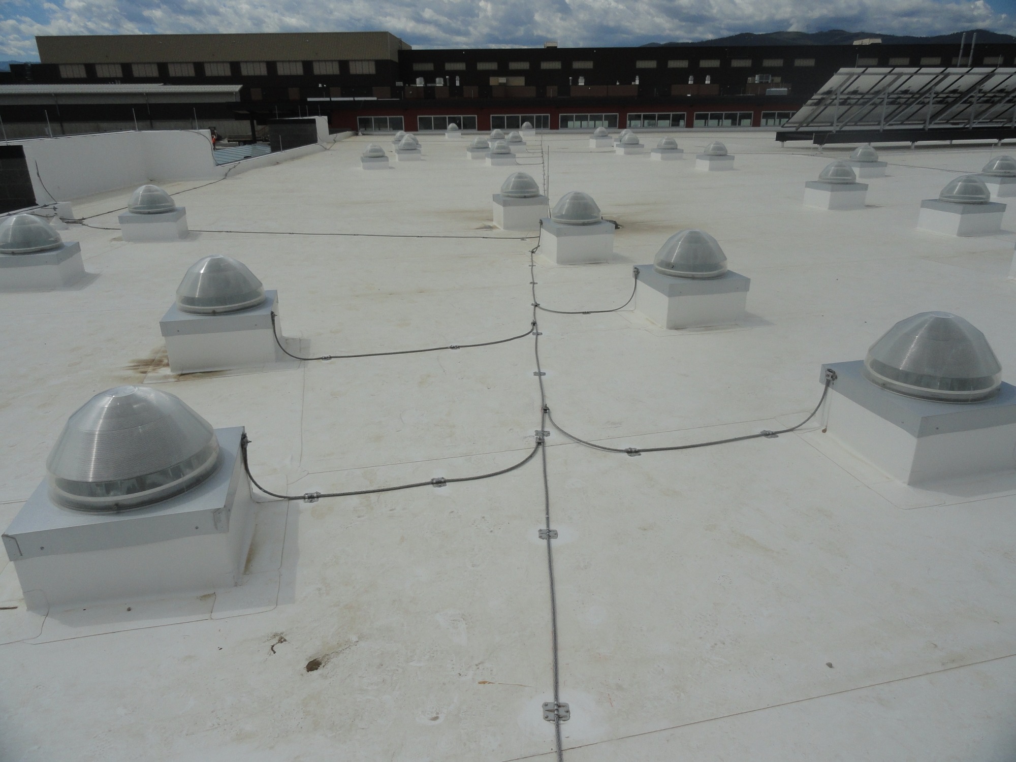 Reference photo showing rooftop bonding conductor runs around skylights and roof penetrations.
